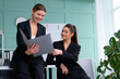 © Andrii - Young women leaders are checking financial statements from paper documents. Two female confident business worker dressed black suit in office checking financial document