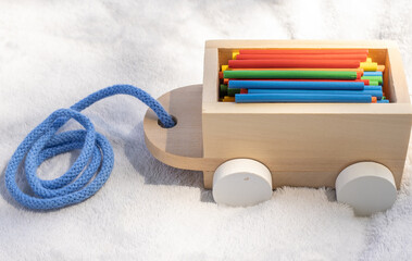 wooden train wagon full of counting colorful sticks.multicolor eco wood material match stick for learning mathematics in primary school on grey blanket,green grass,sunshine.back to school concept,fall