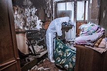 A Specialist In A Protective Suit From A Cleaning Company Cleans A Destroyed Housing After A Fire