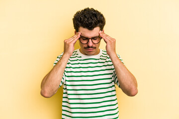 Wall Mural - Young caucasian man isolated on yellow background touching temples and having headache.