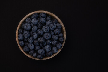 Wall Mural - blueberries in wooden bowl isolated on black