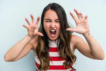 Wall Mural - Young caucasian woman isolated on blue background showing claws imitating a cat, aggressive gesture.