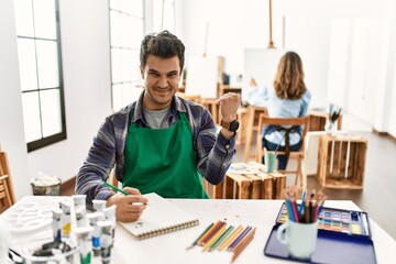 Poster - Young artist man at art studio very happy and excited doing winner gesture with arms raised, smiling and screaming for success. celebration concept.