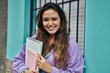 © Krakenimages.com - Young hispanic student woman smiling happy holding books at the city.
