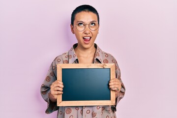 Sticker - Beautiful hispanic woman with short hair holding blackboard angry and mad screaming frustrated and furious, shouting with anger looking up.