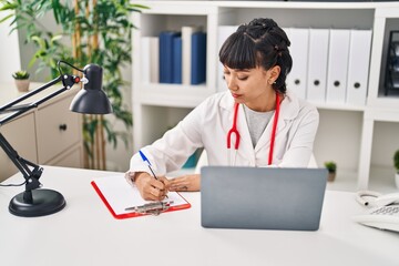 Sticker - Young woman wearing doctor uniform using laptop at clinic