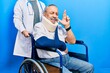 Handsome senior man with beard sitting on wheelchair with neck collar gesturing finger crossed smiling with hope and eyes closed. luck and superstitious concept.