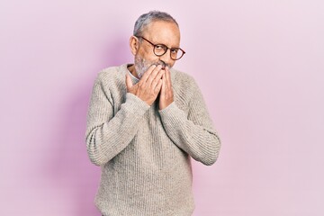 Wall Mural - Handsome senior man with beard wearing casual sweater and glasses laughing and embarrassed giggle covering mouth with hands, gossip and scandal concept