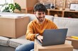 © Krakenimages.com - Young hispanic man smiling confident using laptop at new home