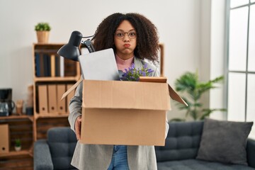 Sticker - Young african american woman moving to a new office holding box with items puffing cheeks with funny face. mouth inflated with air, catching air.