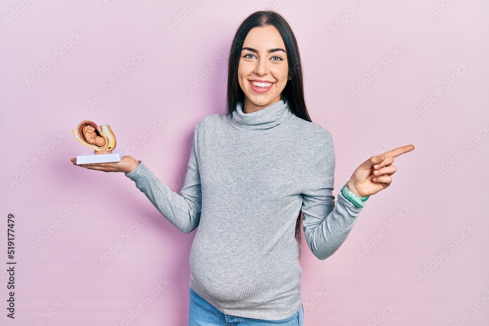Beautiful woman with blue eyes expecting a baby, holding anatomic fetus ...