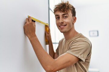 Sticker - Young caucasian man smiling confident measuring wall at home