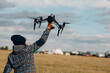 © primipil - FPV drone pilot holding quadcopter drone in hands at outside field