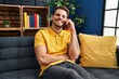 © Krakenimages.com - Young hispanic man talking on the smartphone sitting on sofa at home