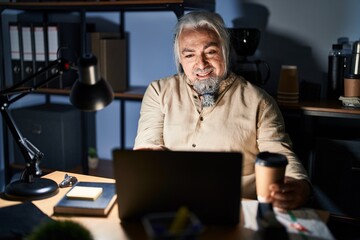 Poster - Middle age man with grey hair working at the office at night smiling cheerful offering palm hand giving assistance and acceptance.