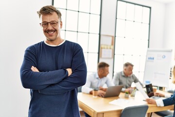 Wall Mural - Middle age caucasian businessman smiling happy standing with arms crossed gesture at the office during business meeting.