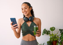 A Young Multi-ethnic Woman Tracks Yoga Session On Fitness App With Green Juice