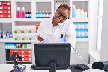 Sticker - African american woman pharmacist talking on telephone reading prescription at pharmacy