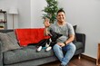 © Krakenimages.com - Young latin man and dog sitting on the sofa at home showing and pointing up with fingers number five while smiling confident and happy.