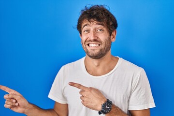 Poster - Hispanic young man standing over blue background pointing aside worried and nervous with both hands, concerned and surprised expression