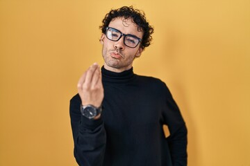 Poster - Hispanic man standing over yellow background doing italian gesture with hand and fingers confident expression