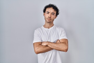 Canvas Print - Hispanic man standing over isolated background skeptic and nervous, disapproving expression on face with crossed arms. negative person.