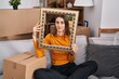 © Krakenimages.com - Young caucasian woman at new home holding empty frame clueless and confused expression. doubt concept.