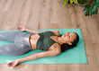 © Meeko Media - A young multi-ethnic woman lies in Shavasana yoga pose at the end of practice