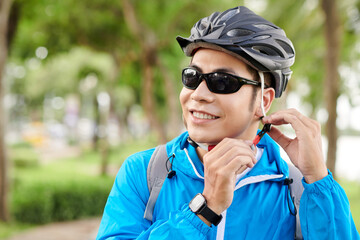 Poster - Smiling sportsman in sunglasses putting on bicycle helmet before ride