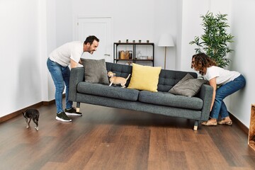 Sticker - Middle age hispanic couple holding sofa at home.