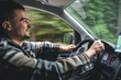 © puhimec - A man driving a car rides in a mountainous forest area.
