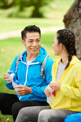 Poster - Positive young man talking to girlfriend and drinking water after long bicycle ride