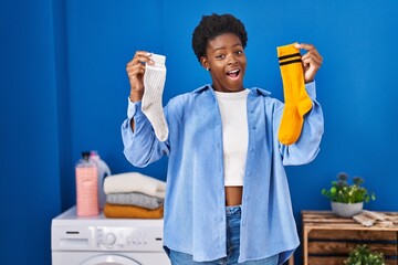 Poster - African american woman holding clean andy dirty socks celebrating crazy and amazed for success with open eyes screaming excited.