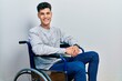 Young hispanic man sitting on wheelchair with a happy and cool smile on face. lucky person.