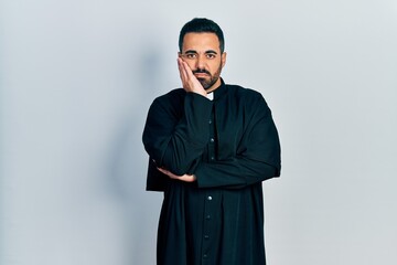 Canvas Print - Handsome hispanic man with beard wearing catholic priest robe thinking looking tired and bored with depression problems with crossed arms.