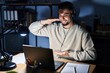 © Krakenimages.com - Young handsome man working using computer laptop at night gesturing with hands showing big and large size sign, measure symbol. smiling looking at the camera. measuring concept.