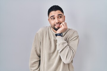 Canvas Print - Young handsome man standing over isolated background looking stressed and nervous with hands on mouth biting nails. anxiety problem.