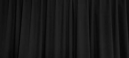 close up view of dark black curtain in thin and thick vertical folds made of black out sackcloth fabric, panoramic view of drapery use as background. textured abstract backgrounds and wallpapers.