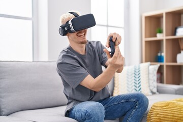 Young caucasian man playing video game using virtual reality glasses at home