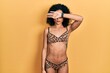 Young latin girl wearing bikini covering eyes with arm, looking serious and sad. sightless, hiding and rejection concept