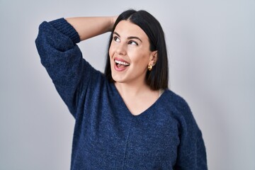 Canvas Print - Young brunette woman standing over isolated background smiling confident touching hair with hand up gesture, posing attractive and fashionable