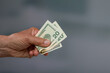 close-up of a man's hand holding a bunch of dollar bills / greenbacks