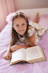 Wall Mural - a girl of eight years reads a book