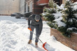 A man cleans and clears the snow in front of the house on a sunny and frosty day. Cleaning the street from snow on a winter day. Snowfall, and a severe snowstorm in winter.