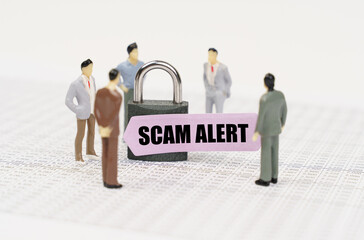 There are figures of people on business reports, a padlock with a sticker on which it is written - Scam alert