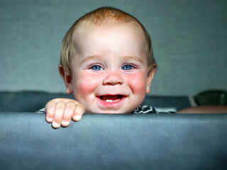 Wall Mural - Funny baby boy toddler peeking out of the crib.