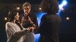 © Framestock - An actress and an actor rehearsing a love scene on a theater stage with a spotlight while a male director watching them