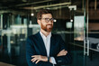 © Prostock-studio - Portrait of successful businessman in suit posing with crossed hands, looking away and smiling, copy space