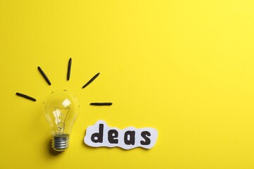 Wall Mural - Word Ideas made with lightbulb and paper sheet on yellow background, flat lay. Space for text