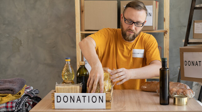 Portrait of smiling man volunteer packing a donation box in office